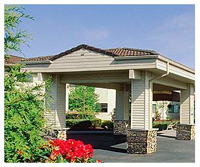 Entrance of a hotel with landscaped surroundings.