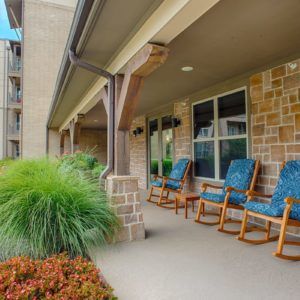 A cozy patio with rocking chairs and lush landscaping.