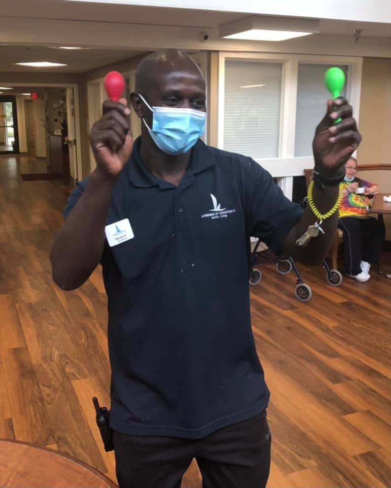 A person wearing a mask holds red and green maracas indoors.