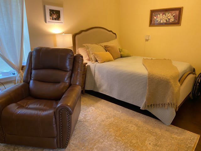 A cozy bedroom with a comfortable bed and a brown leather recliner.