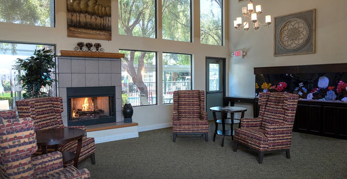 A cozy living room featuring a fireplace, comfortable chairs, and large windows.