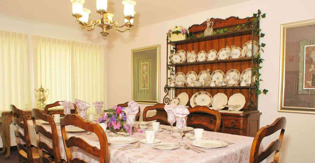 A well-decorated dining room featuring a table set for a meal, complete with fine china and a floral centerpiece.