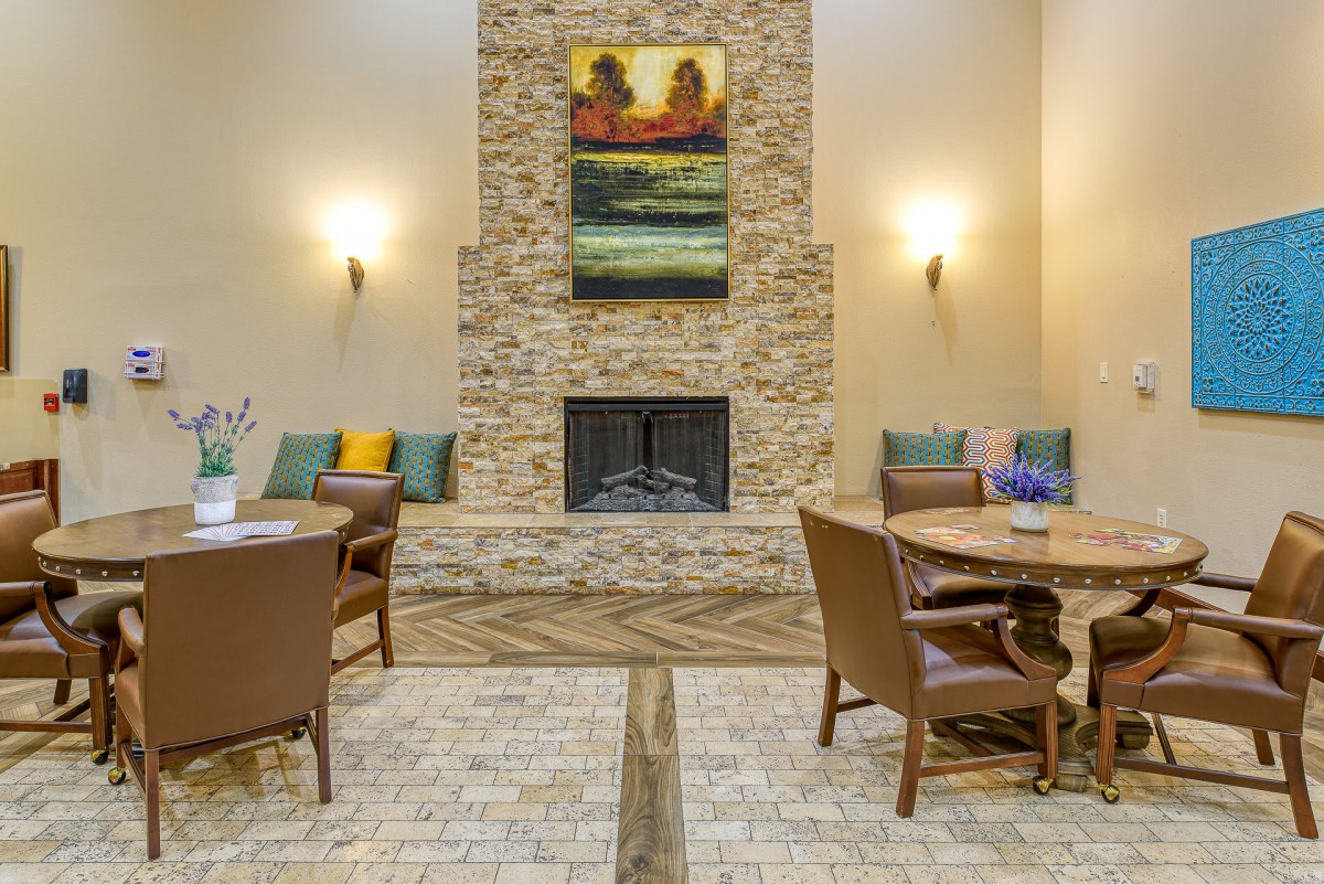 A modern living room featuring a central fireplace surrounded by brick, with comfortable seating and contemporary artwork.