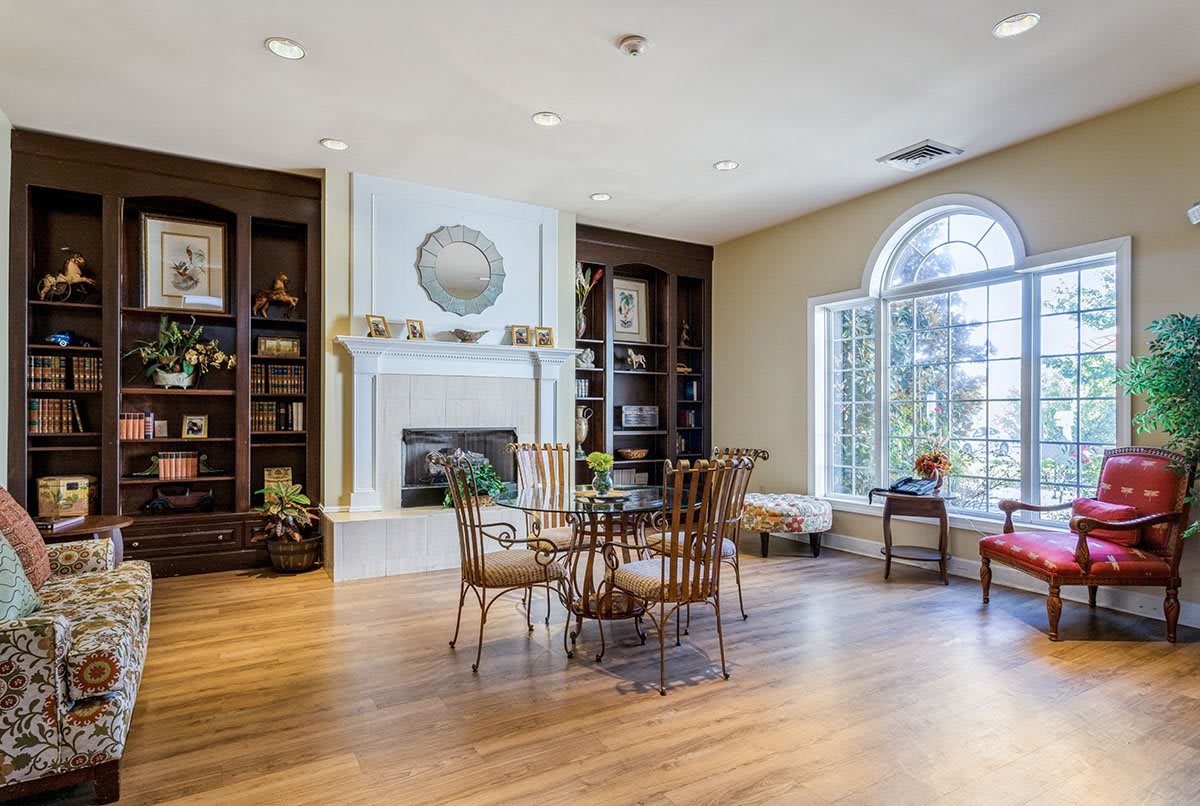 A cozy living room with a central fireplace, surrounded by bookshelves, and featuring a stylish seating area with wooden flooring.