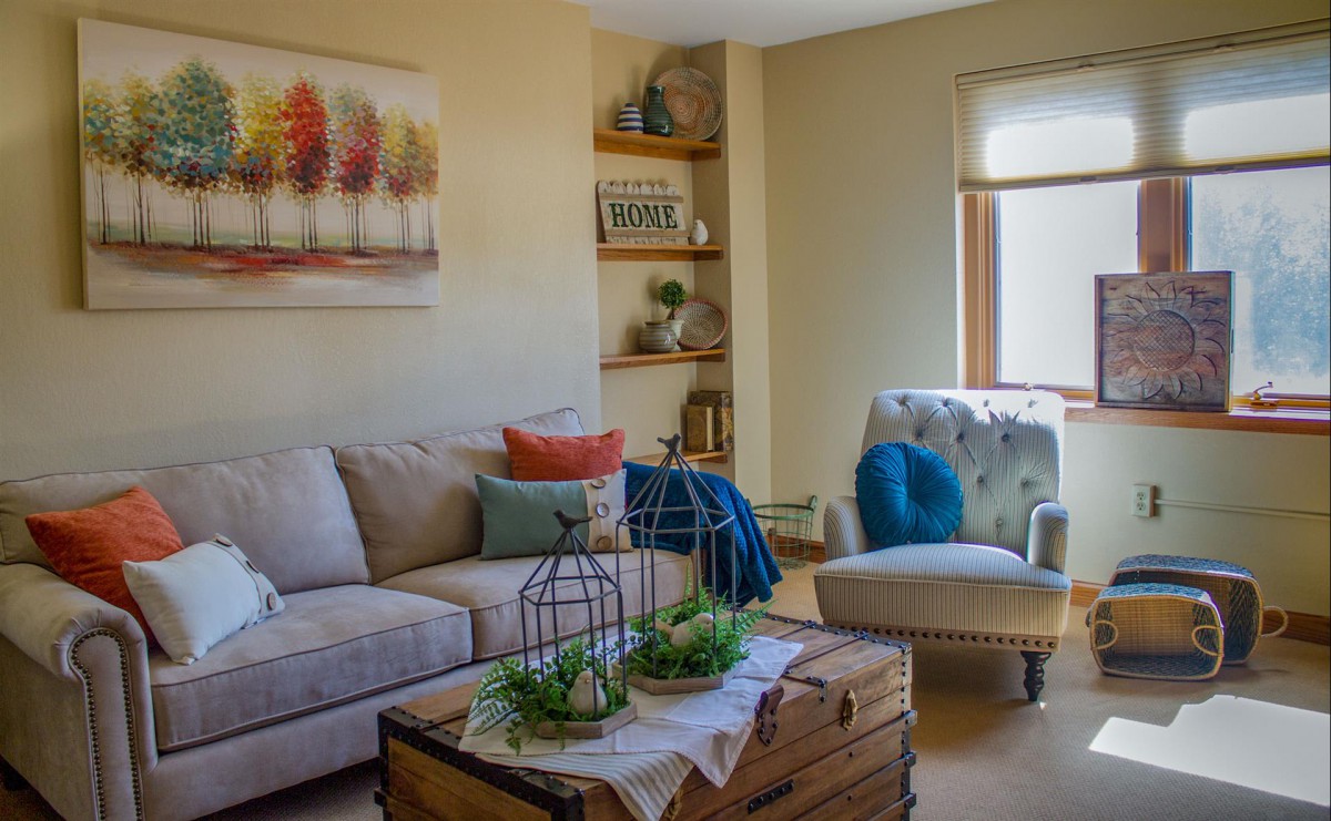 A cozy living room with a neutral color palette, featuring a comfortable sofa, armchair, and colorful decor accents.