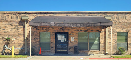 Front view of a brick office building with a dark awning and a single entrance door.