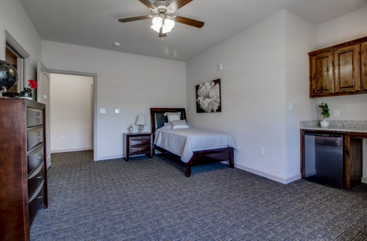 A minimalist bedroom with a single bed, nightstand, and carpeted floor.