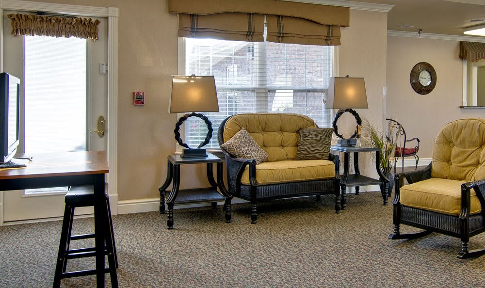 A cozy living room with a yellow sofa, two lamps on side tables, and a large window.