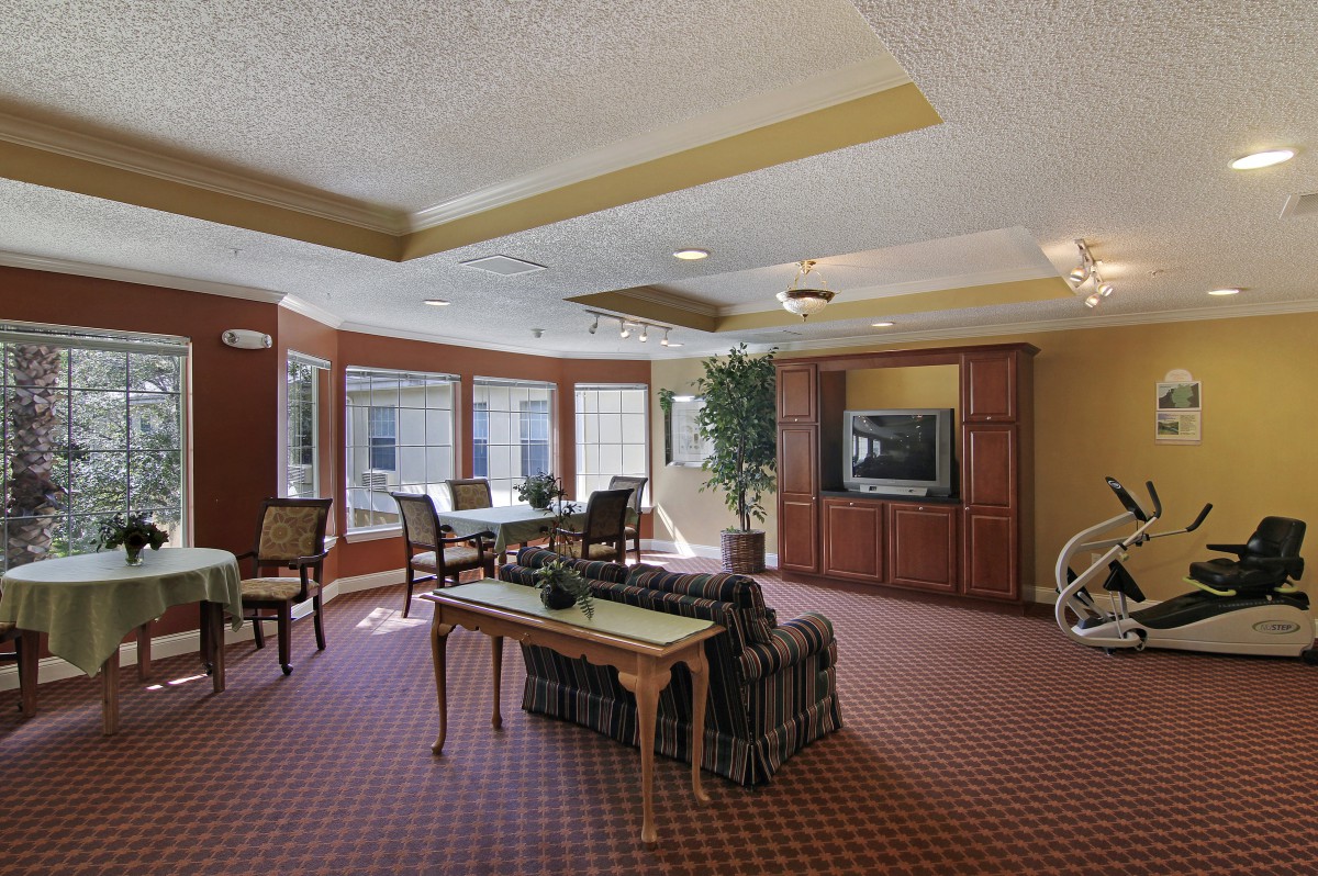 A spacious living room with a television, seating area, and large windows.