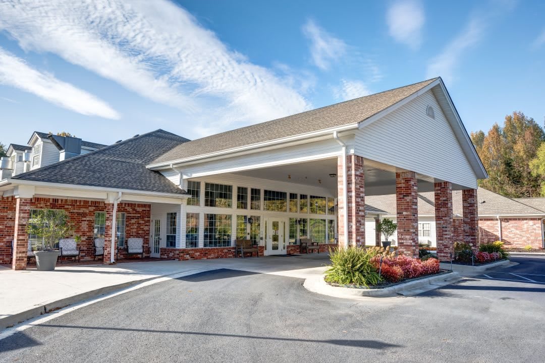 A well-maintained building entrance with brick accents and a covered driveway under a clear sky.
