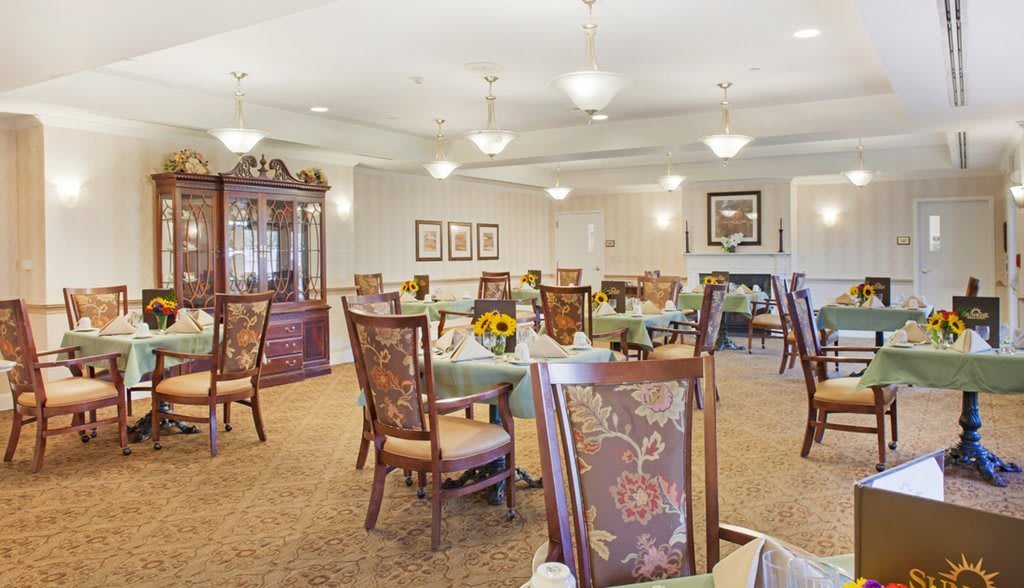 A cozy dining room with elegant chairs and tables, decorative lighting, and carpeted flooring.