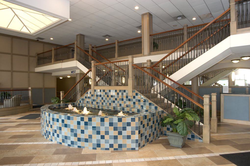 A spacious lobby featuring a decorative tiled fountain and a dual staircase.