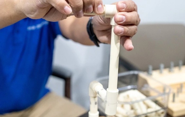 A person assembling a structure using PVC pipes.