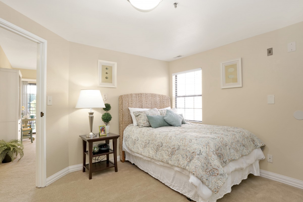 A cozy bedroom with a bed, side table, lamp, and wall decor.