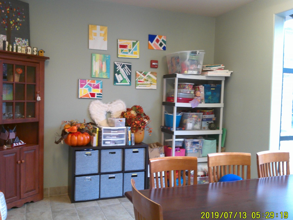 A cozy art room with shelves filled with various art supplies and colorful decorations on the wall.