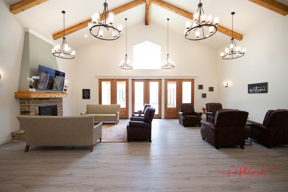 Spacious living room with rustic chandeliers and wood beam accents.