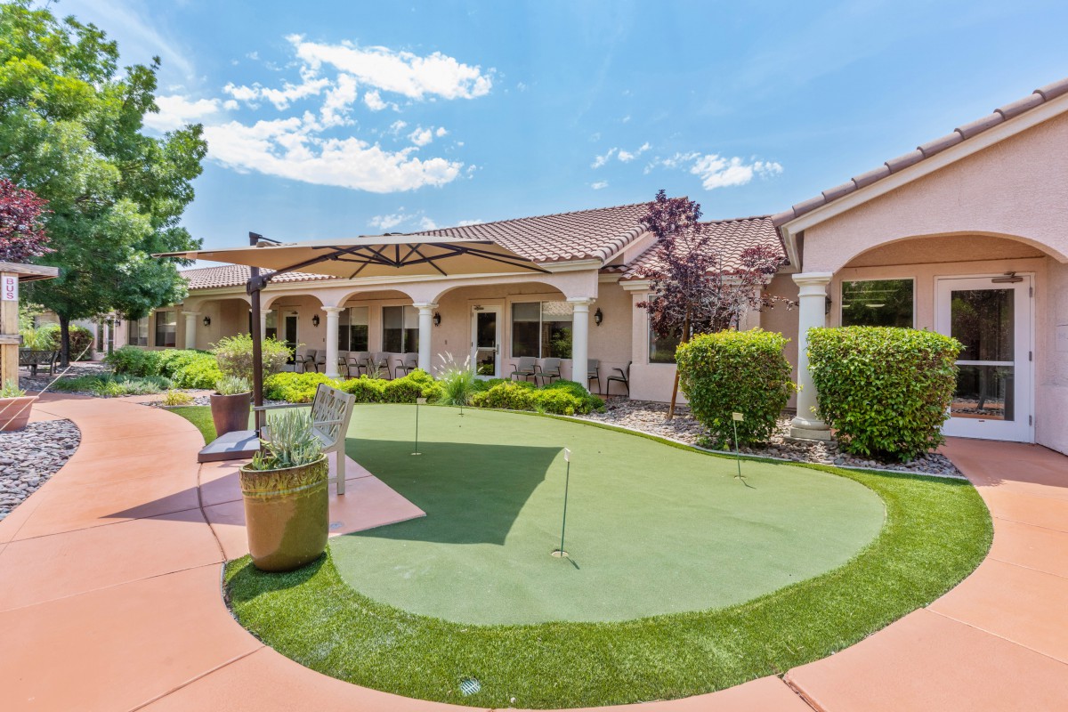 A backyard view of a house featuring a patio and a putting green.