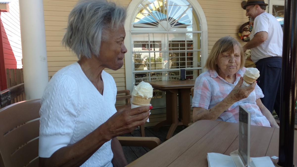 Two people enjoying ice cream and conversation outdoors on a sunny day.