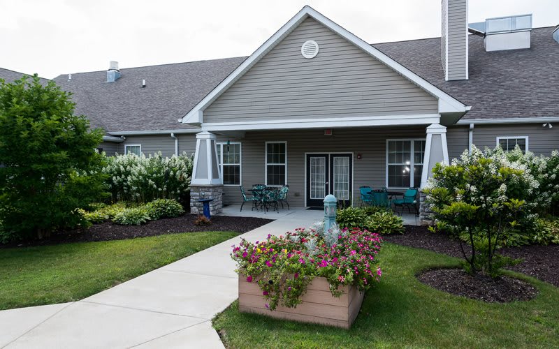 A quaint house with a well-maintained garden and a flower-filled planter by the entrance.