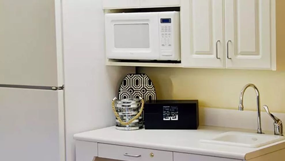 A kitchen countertop with a microwave, decorative bucket, and patterned tray.