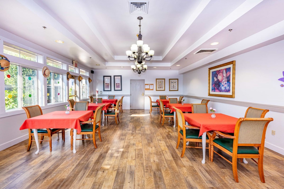 A well-lit dining area with red tablecloths and wooden floors.