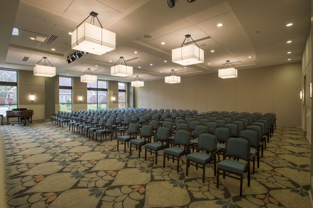 An empty conference room setup with rows of chairs and overhead lighting.