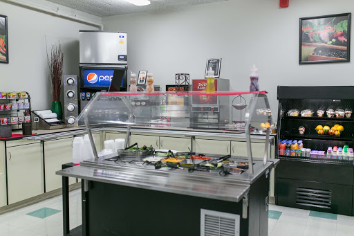 A view of a food service area featuring a counter with condiment options and beverage dispensers.