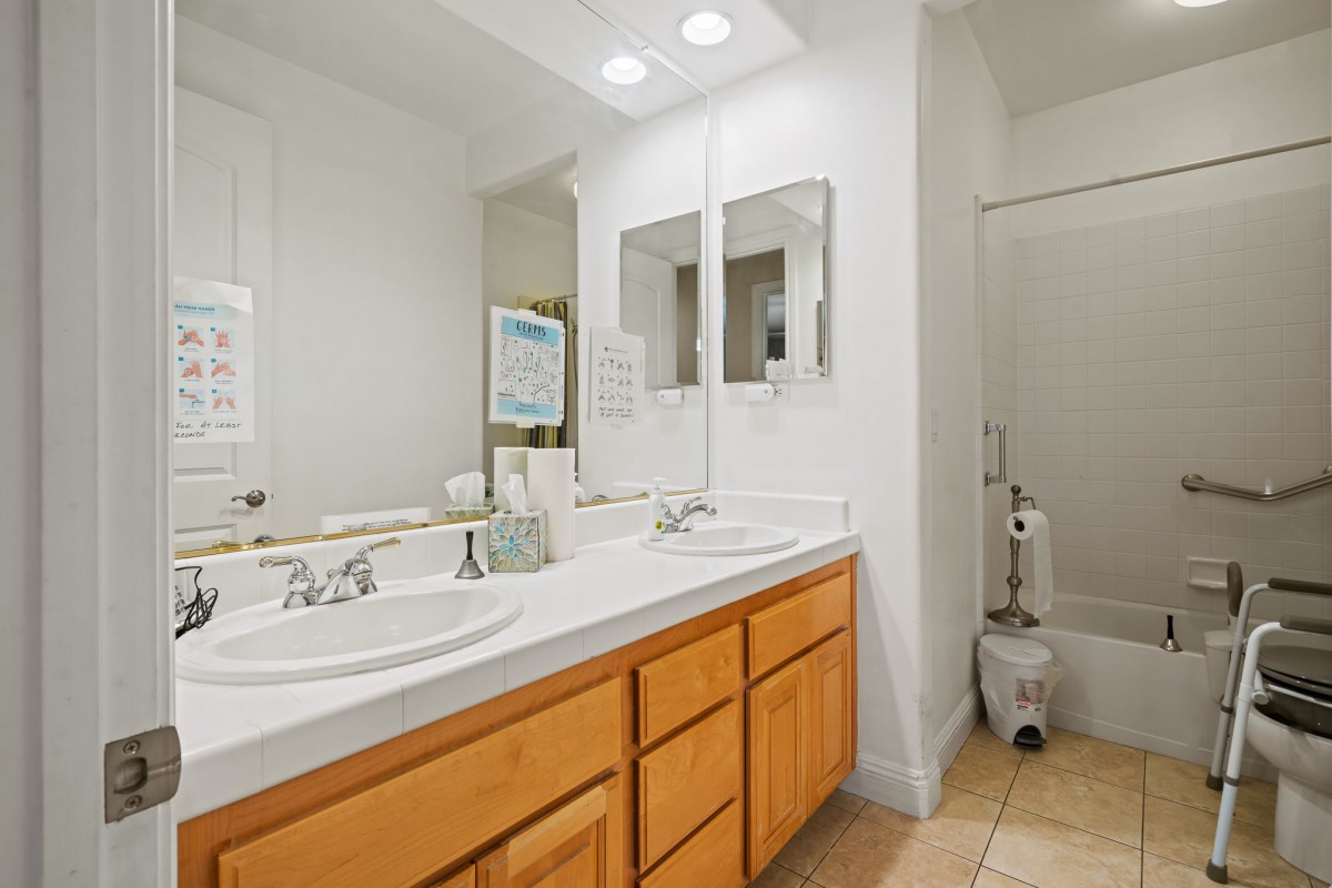 A modern bathroom with dual sinks, mirrors, and wooden cabinetry.