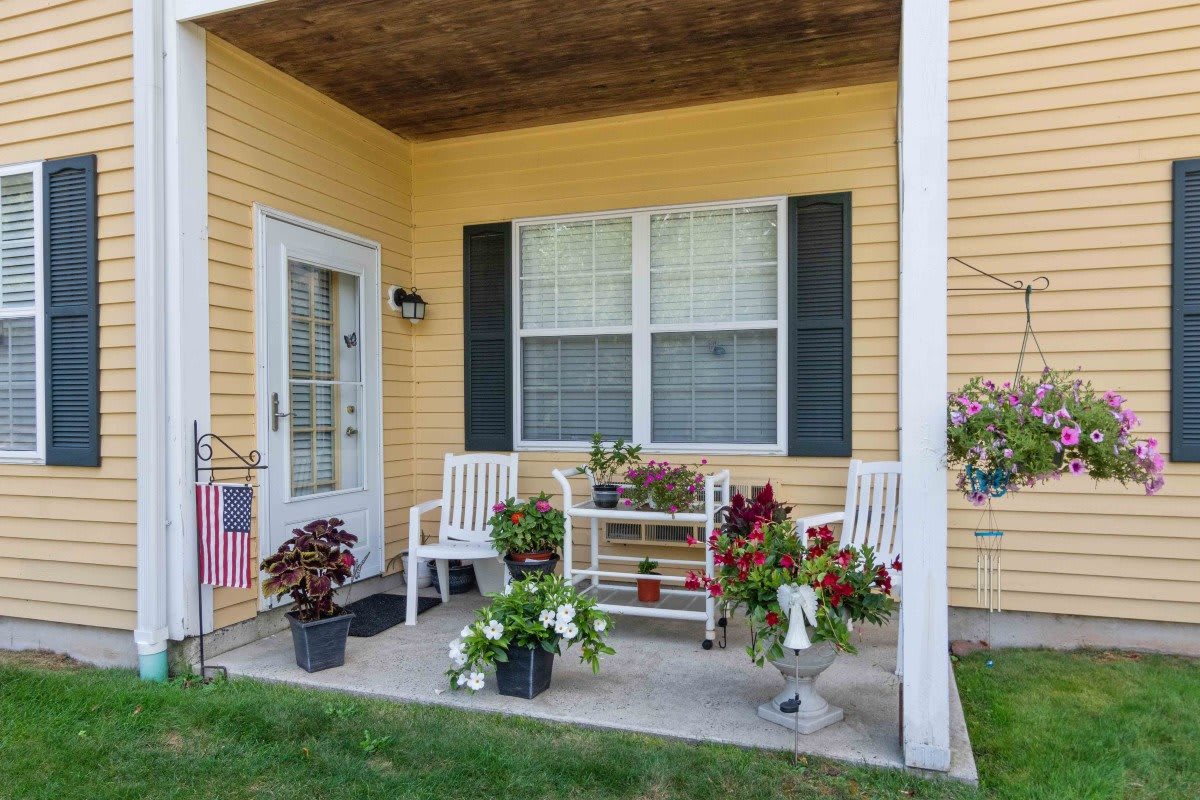 A cozy porch with chairs and vibrant potted plants.