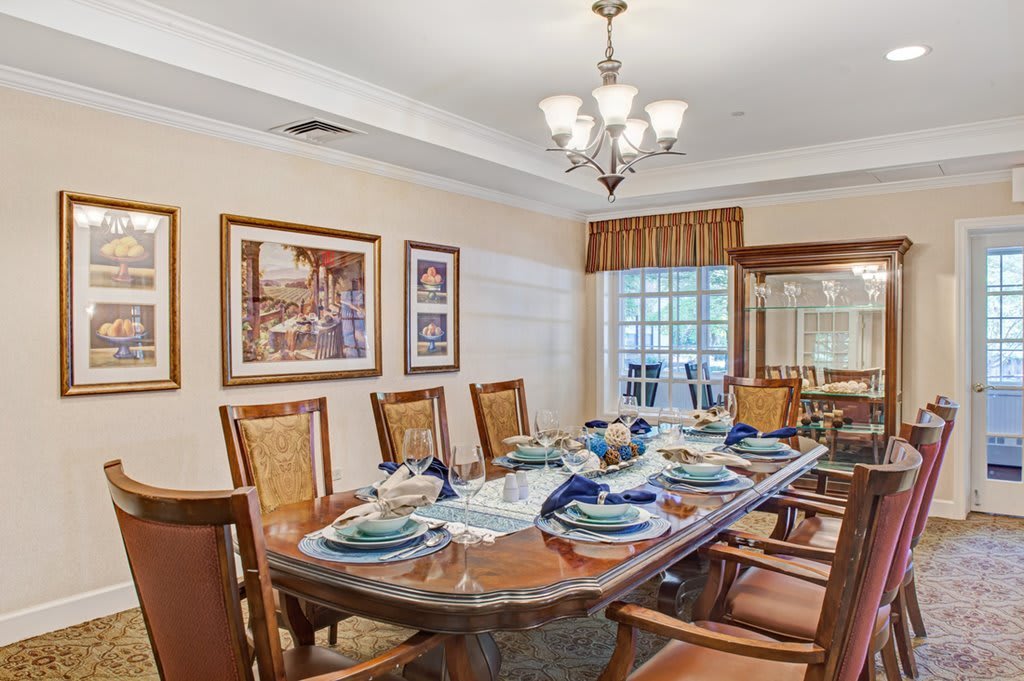 A well-appointed dining room with a large table set for a meal, surrounded by chairs and illuminated by a chandelier.