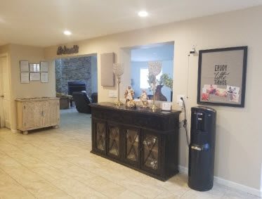 A cozy living room with a dark cabinet, decorative items, and a water dispenser.