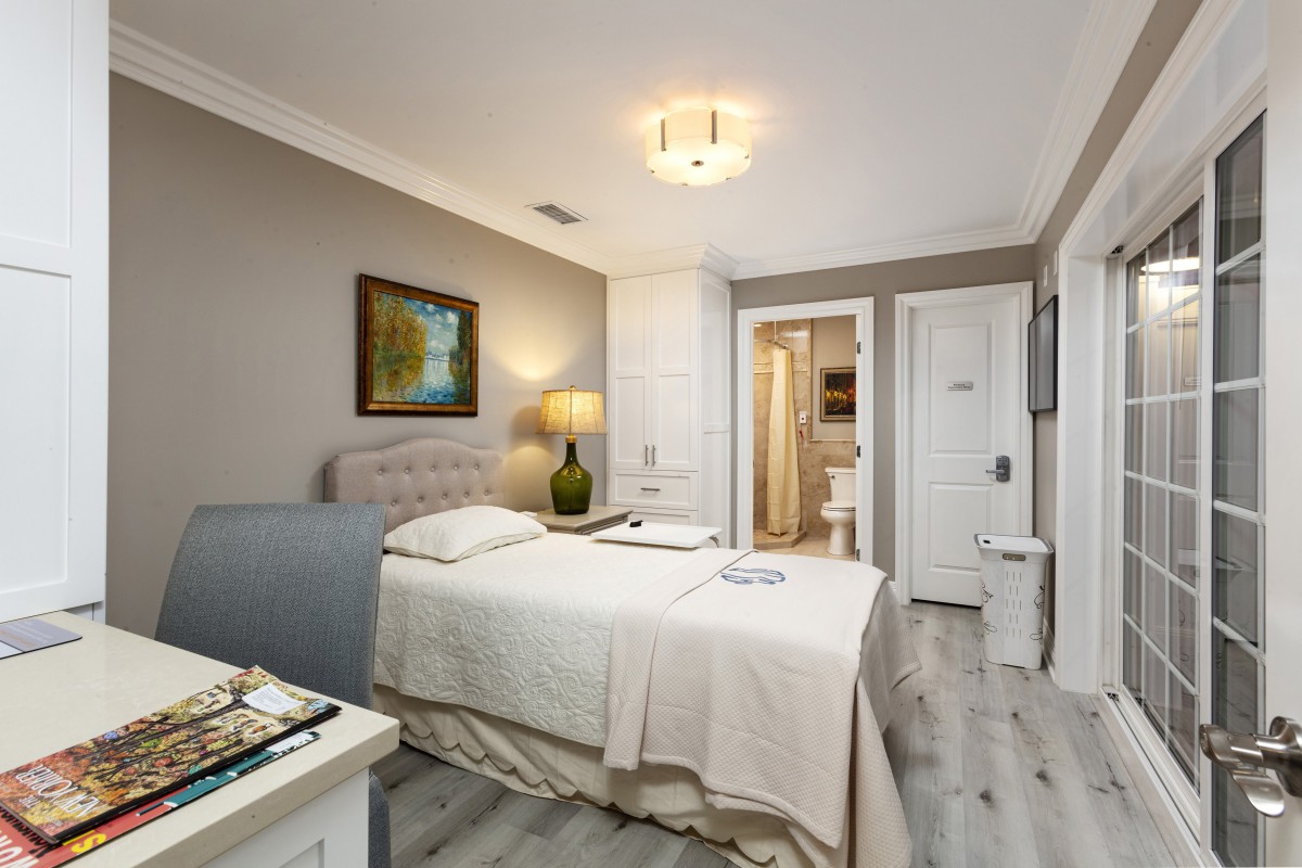 A modern bedroom with a single bed, featuring neutral tones and sleek decor.