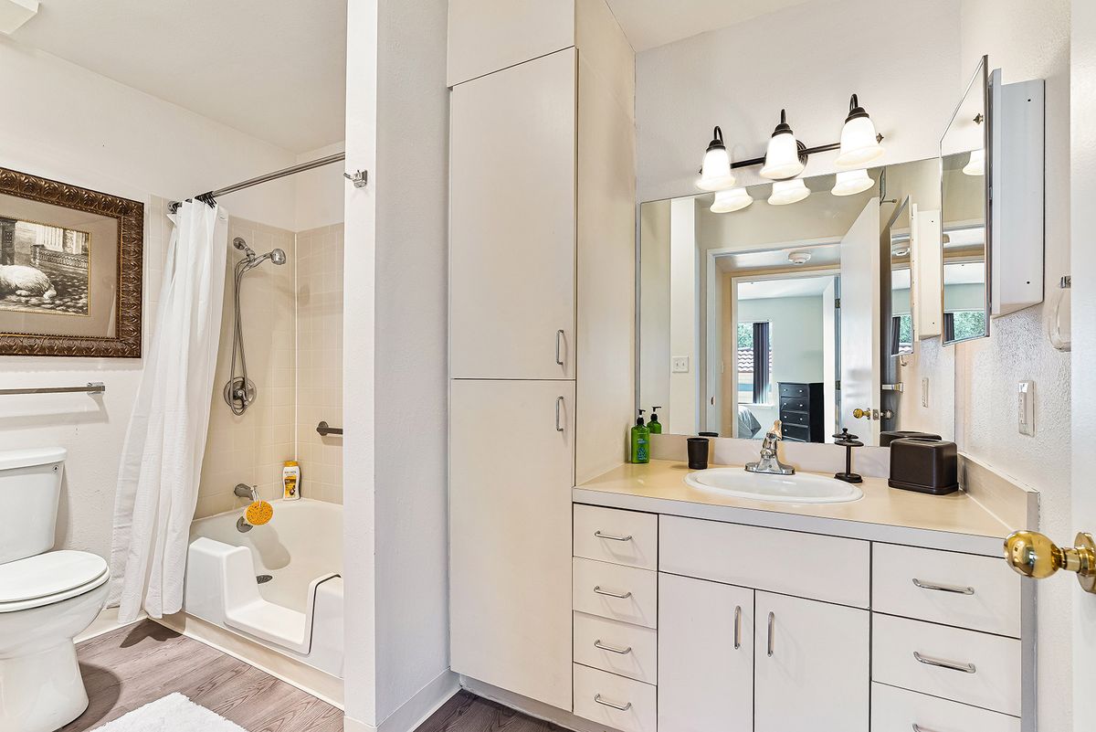A modern bathroom with a white vanity, mirror, and bathtub.