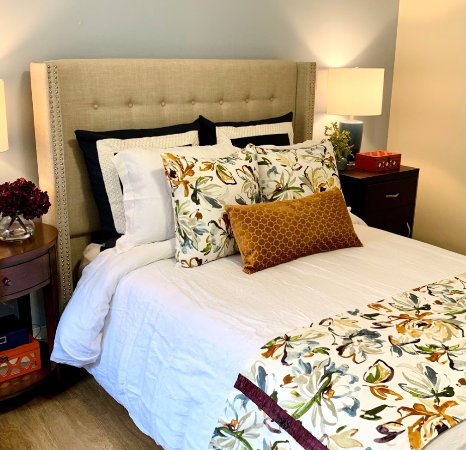 A cozy, well-decorated bedroom featuring a bed with floral patterned bedding and accent pillows.