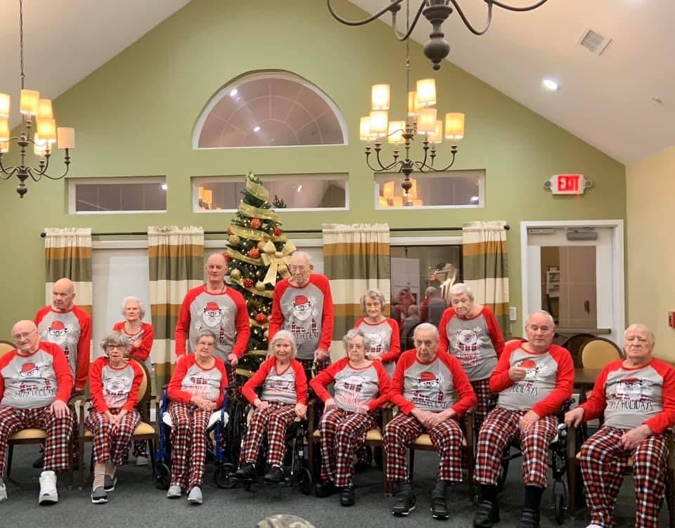 A group of elderly people in matching festive outfits celebrating Christmas indoors.