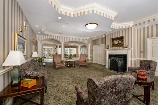 A traditionally decorated living room featuring armchairs, a fireplace, and a chandelier.