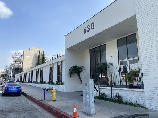 A modern building with a clean design located at 630, featuring large windows and palm trees.