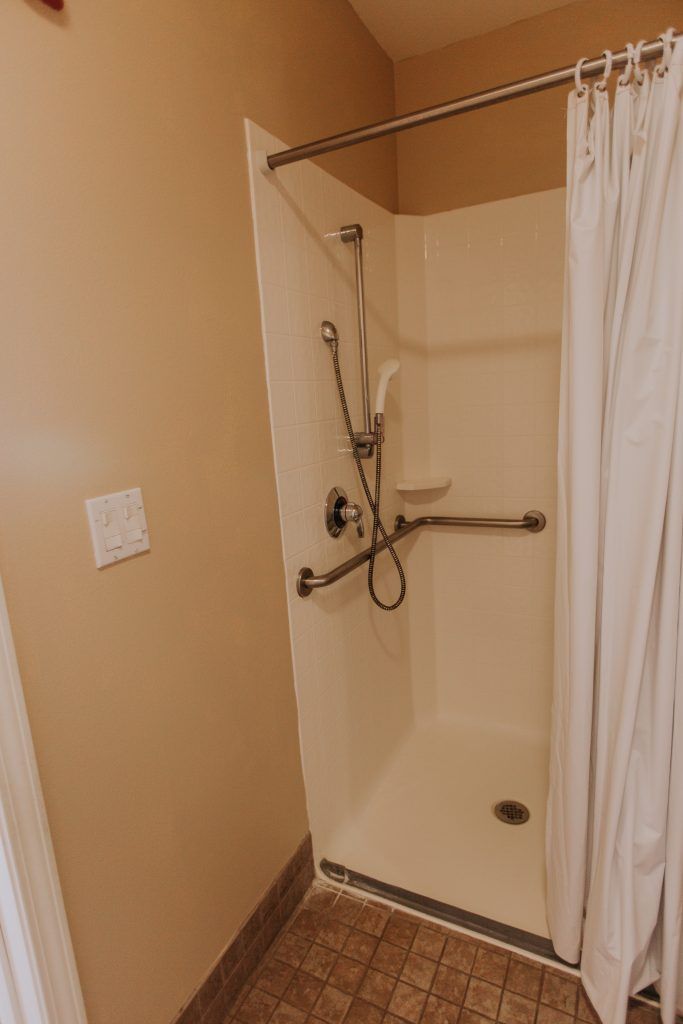 A bathroom shower with a curtain and accessibility features.