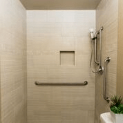 A modern, accessible shower with neutral tile and safety features.