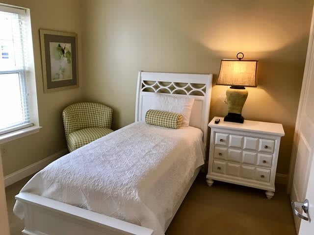 A cozy bedroom with a single bed, nightstand, and lamp.