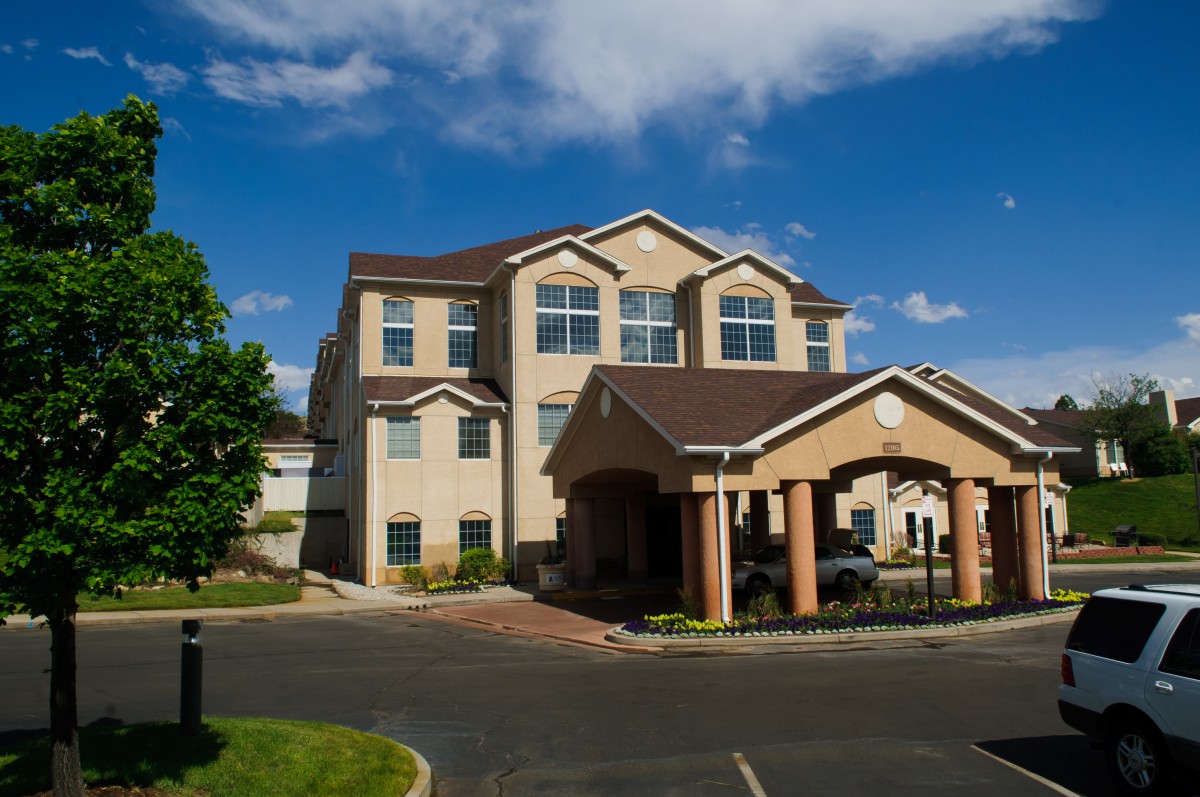 A residential building with a landscaped entrance under a bright blue sky.