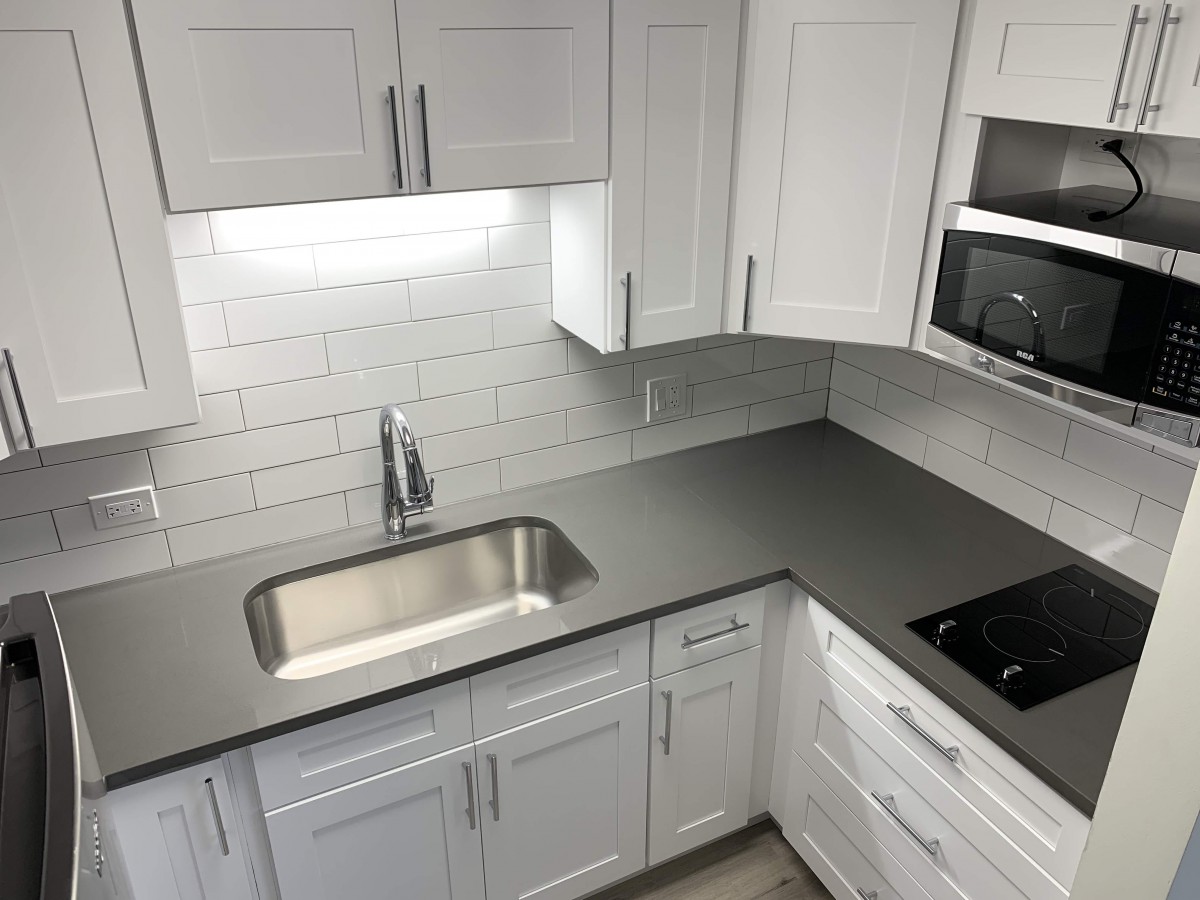 Modern kitchen with white cabinets and a sleek countertop.