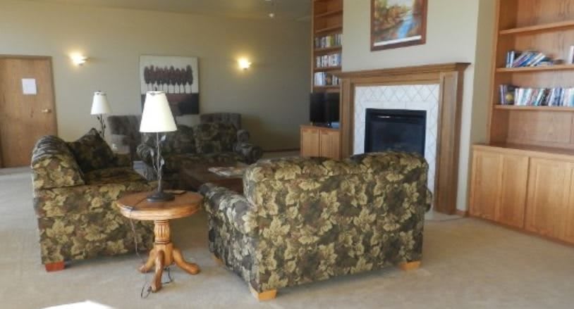A cozy living room featuring camouflage-patterned sofas, a wooden side table with a lamp, and a fireplace.