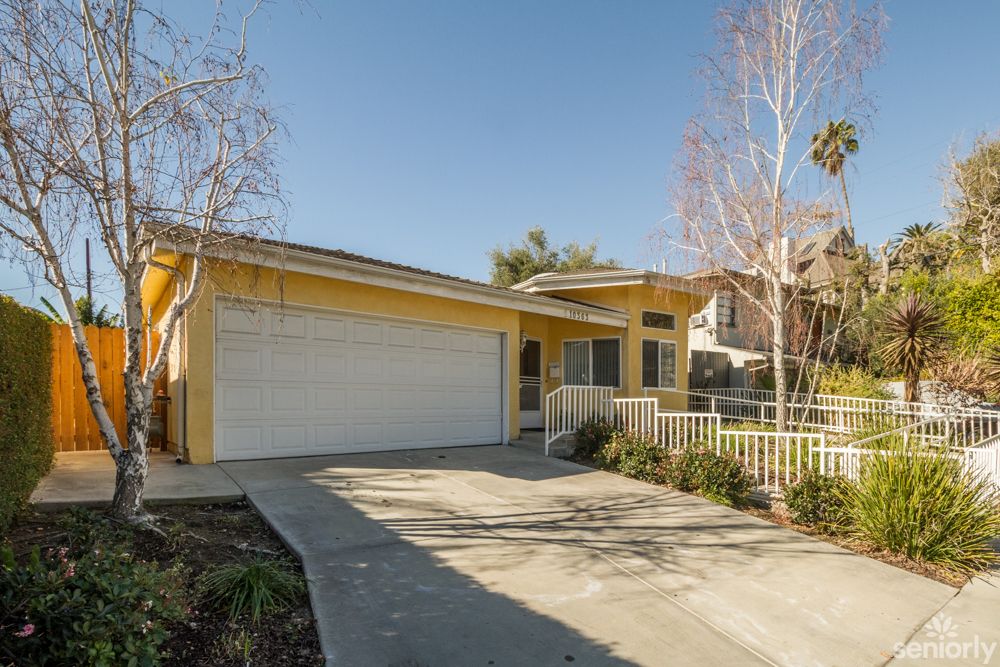 A suburban house with a two-car garage and driveway on a sunny day.