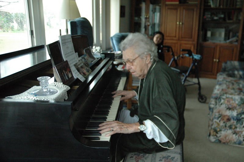 An elderly person playing the piano indoors.