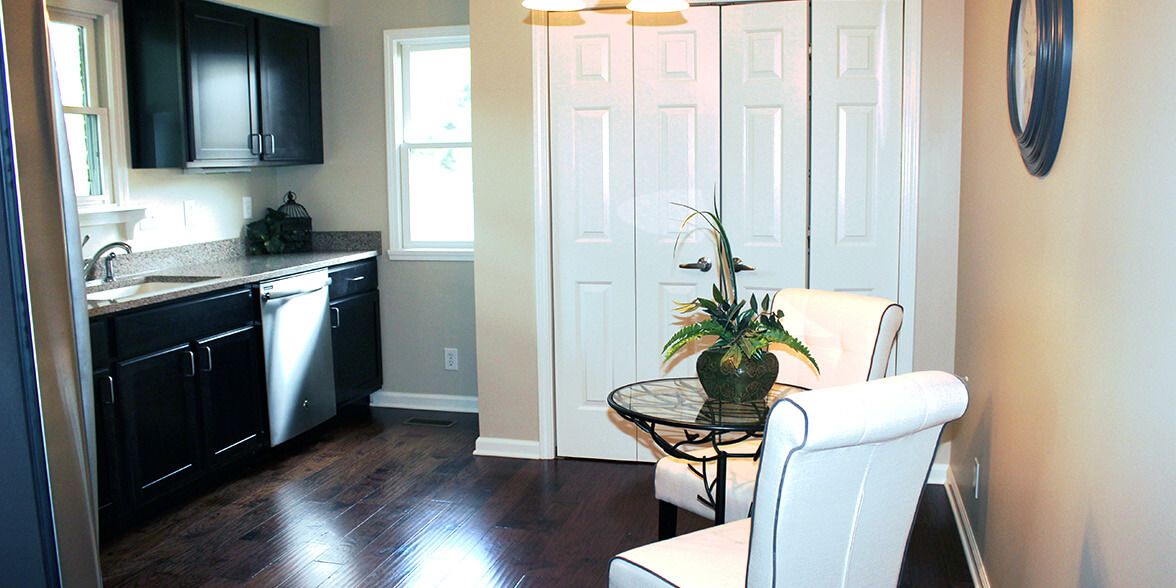 A modern interior featuring a cozy living area with white furniture, a decorative plant, and adjoining kitchen space.