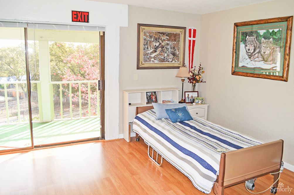 A cozy bedroom with a single bed, striped bedding, and a balcony view.