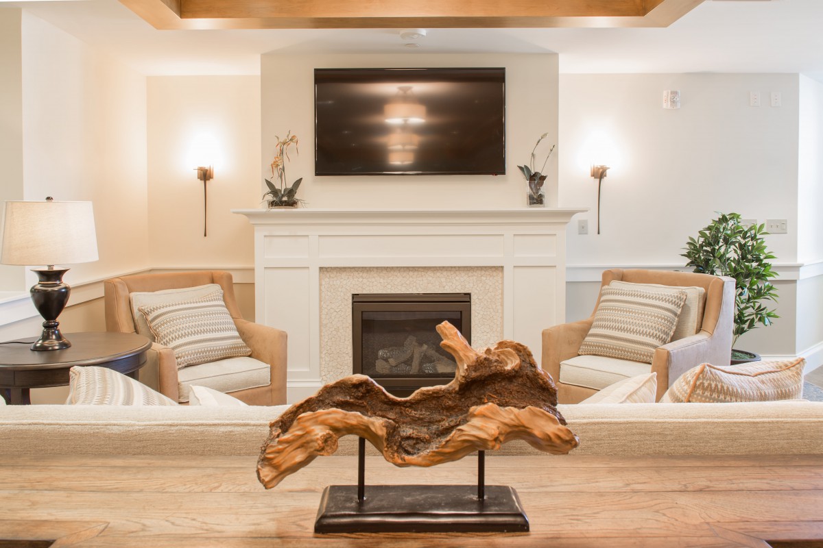 A cozy living room with a modern fireplace and a striking wood sculpture centerpiece.