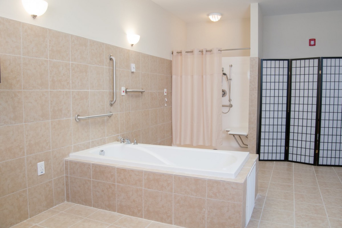 A modern bathroom with a bathtub, shower, and tiled walls.