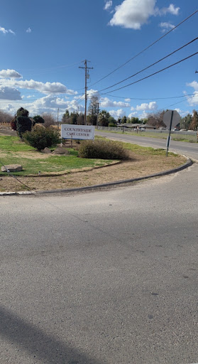 A view of a curved road with a sign and landscaped area.